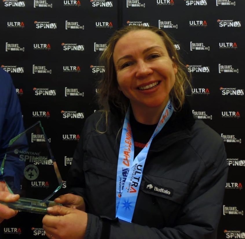 Kendra receives a glass trophy and is wearing a medal with a blue ribbon