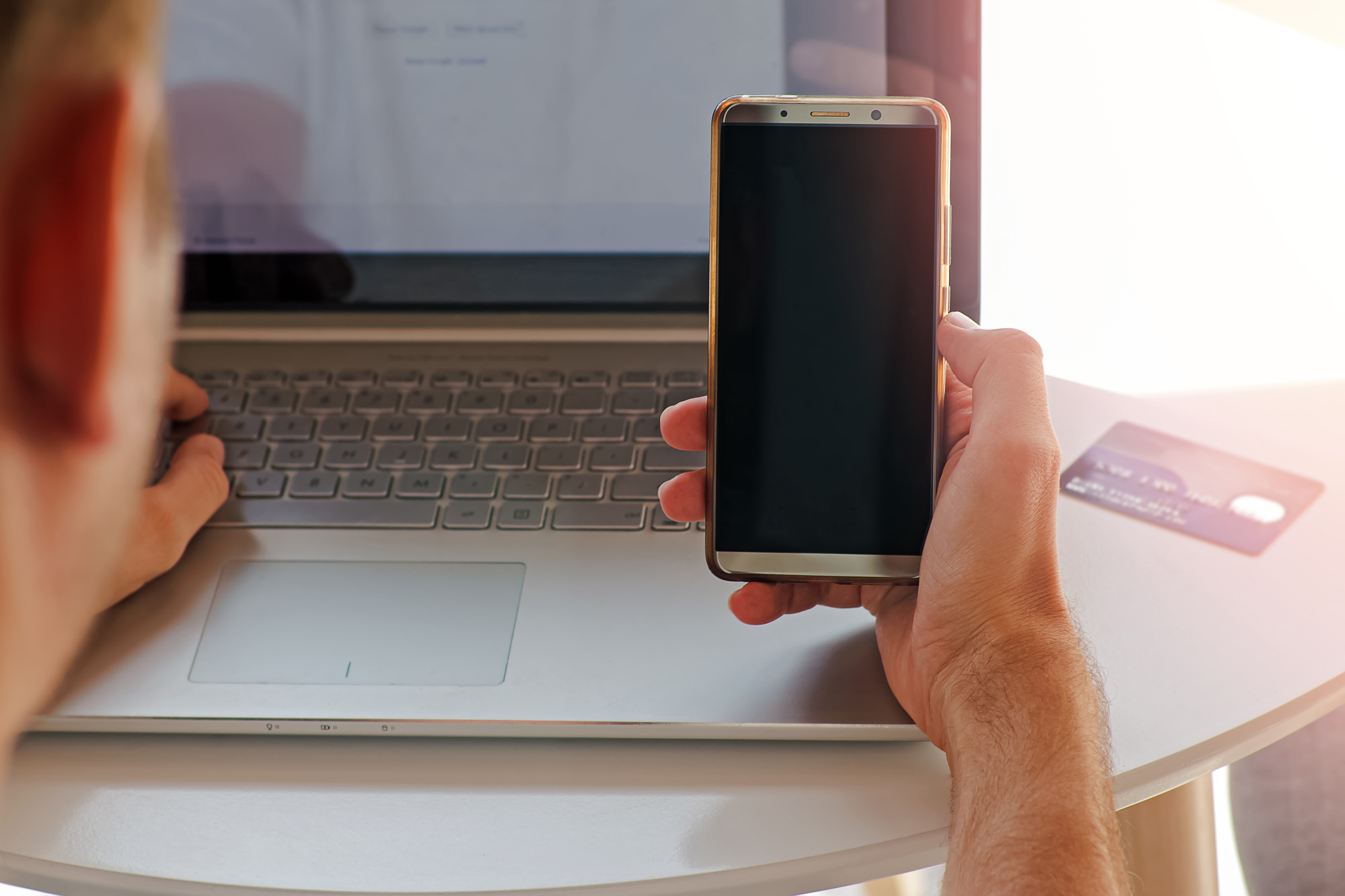 man holding phone in front of laptop