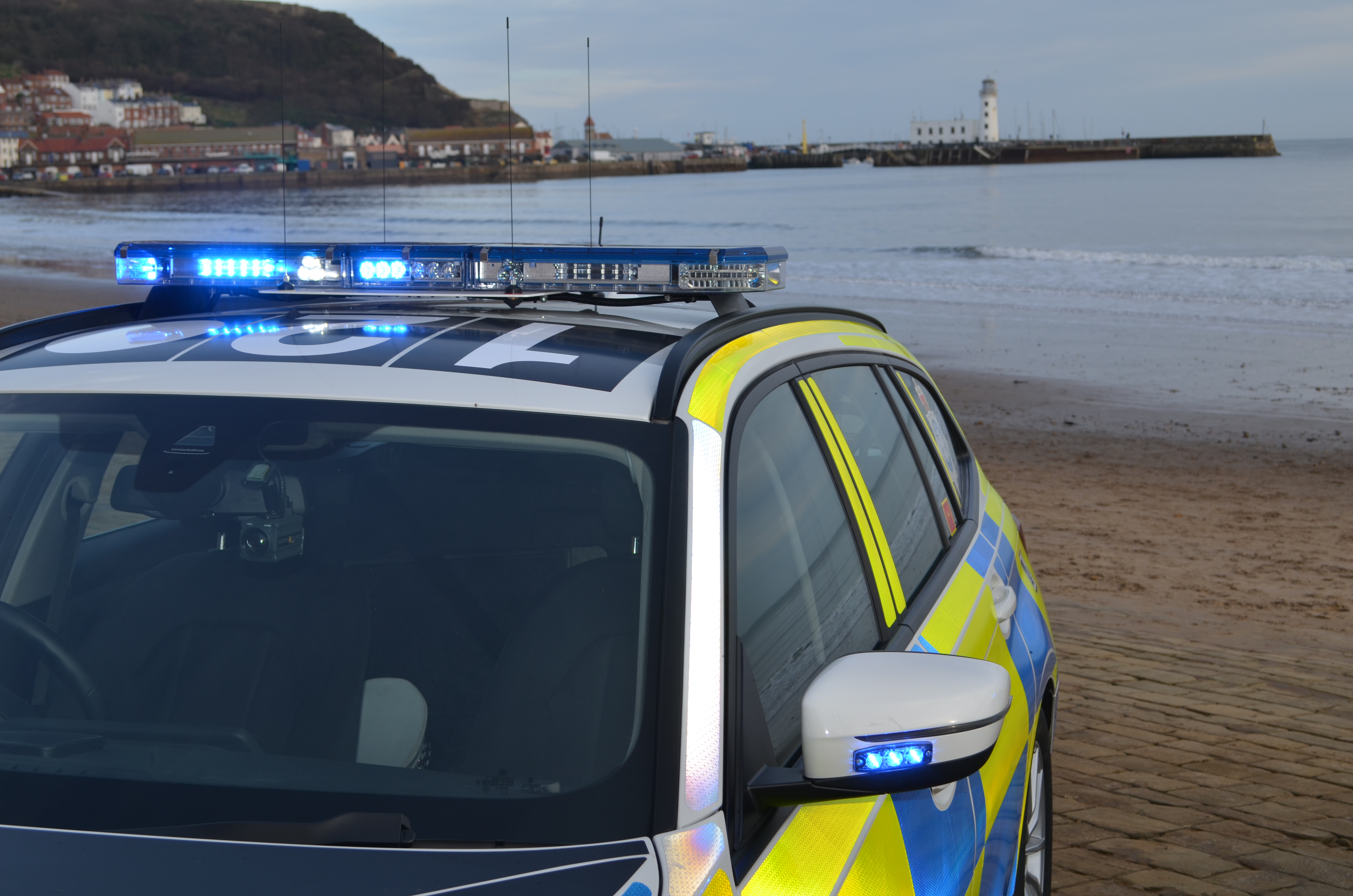 marked police car with blue lights near beach