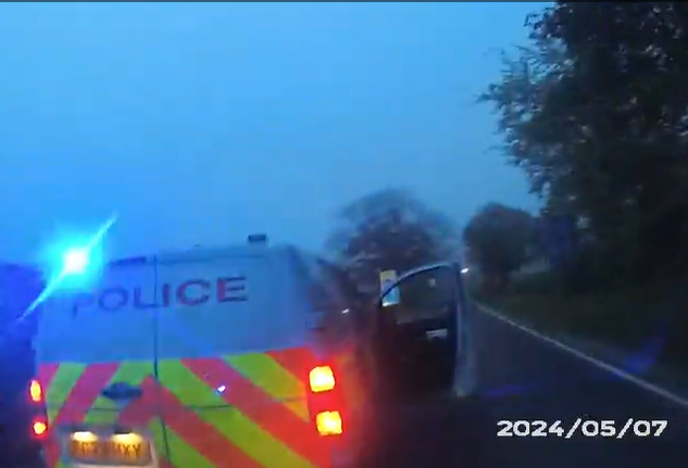 police van with blue light on road at dusk