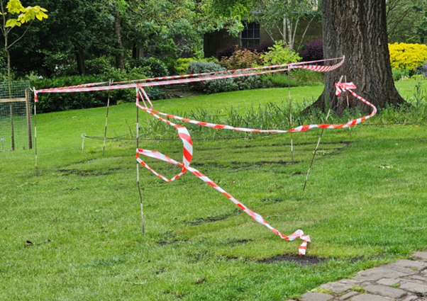 a garden with red and white tape  cordon in the grass