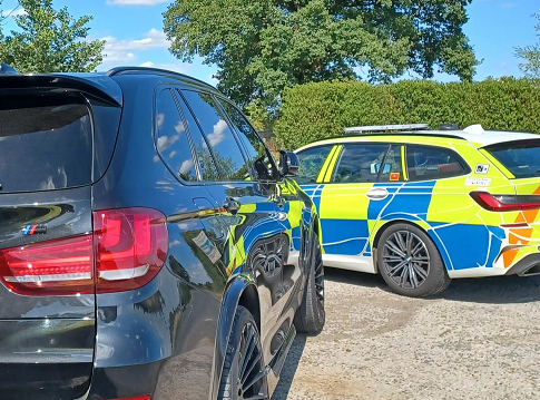 marked police car and plain black car at an angle 