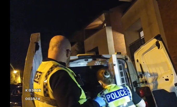 police officers in uniform at the back of a cell van 