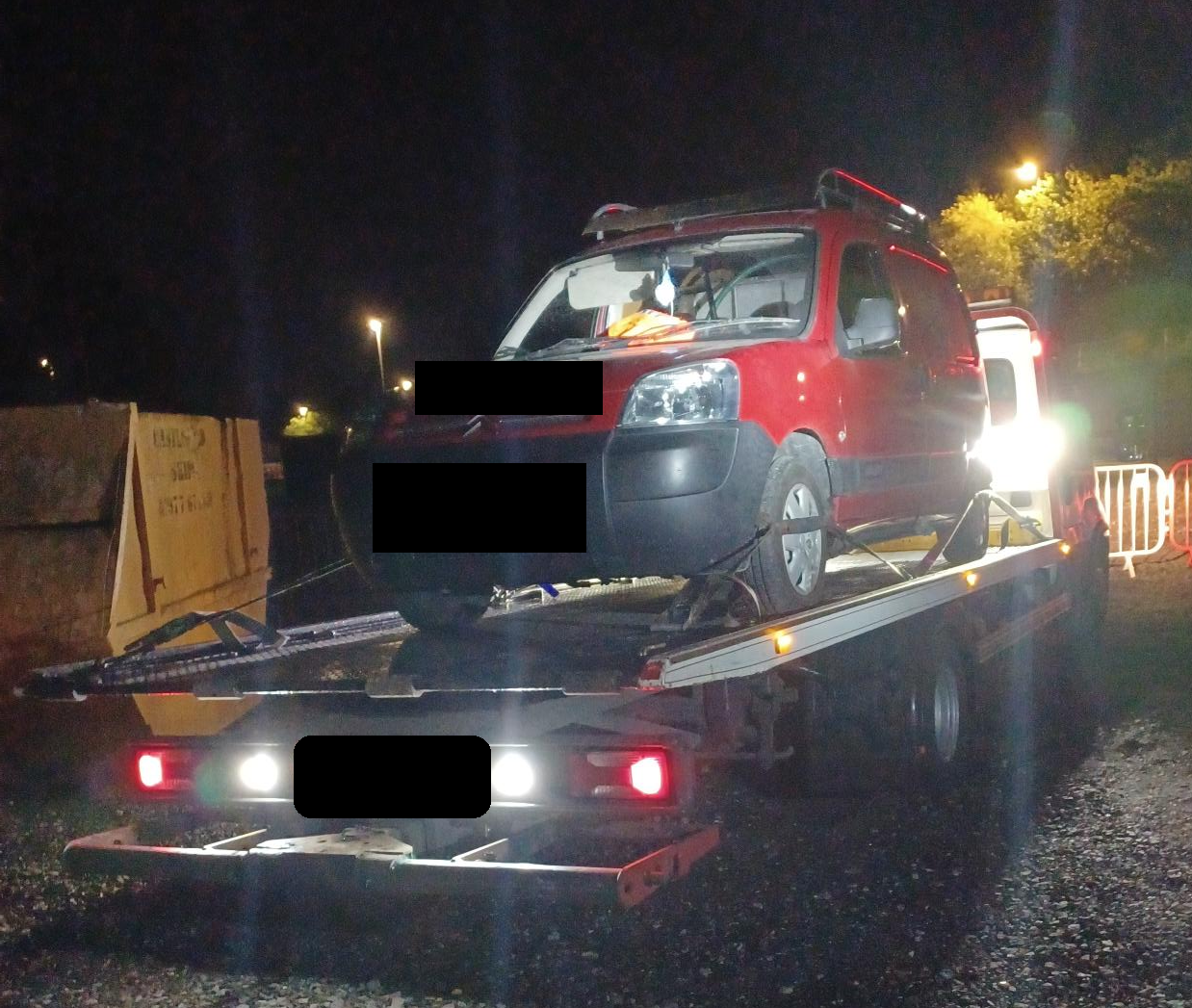 picture of a red van being seized onto the back of a pick up truck