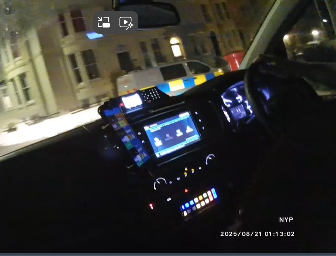 dashboard of police vehicle with police van in the background