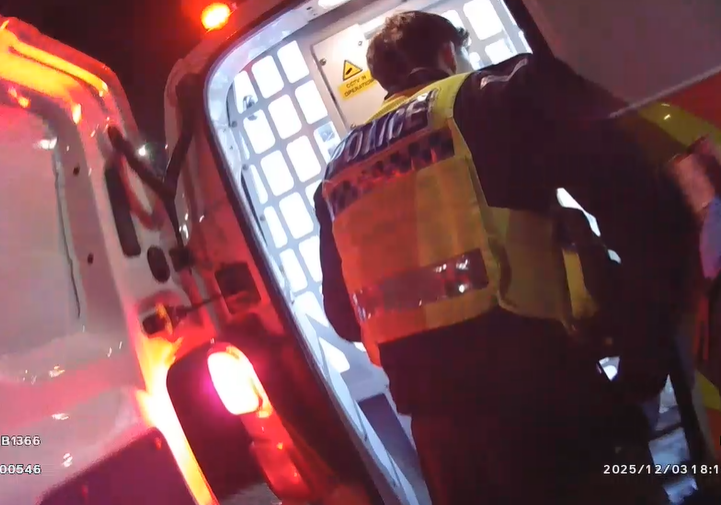 back of police officer in hi-vis jacket and back of police cell van 