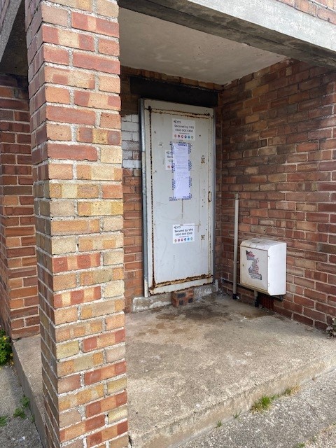 white front door with closure order stuck to it 