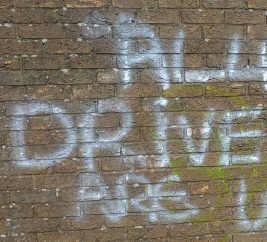 white grafitti on a brick wall in large painted letters 