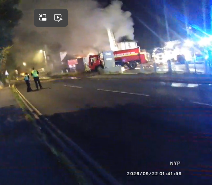 bodyworn video still of scene of fire including lights, fire appliance and smoke 